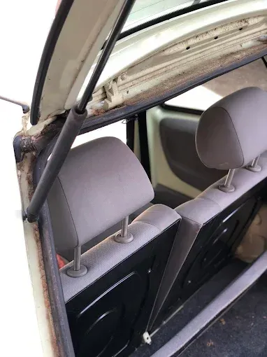 Interior de un coche con portón trasero abierto, con dos reposacabezas grises y portón trasero elevado.