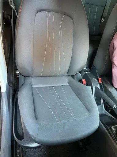Asiento delantero de coche con tapicería gris y negra en el interior de un vehículo.