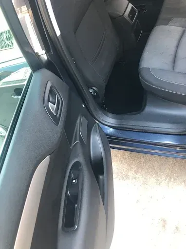 Puerta del coche abierta con interior negro y asiento gris visible