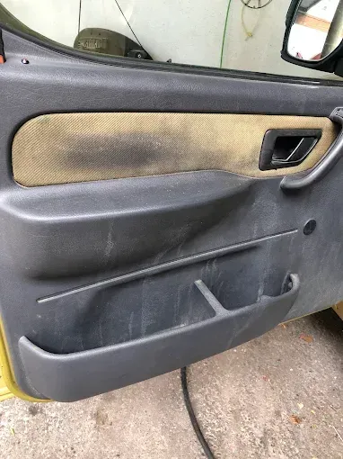 Primer plano del interior de la puerta de un coche gris con paneles de color beige y un bolsillo de almacenamiento