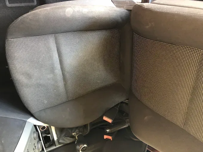 Dos asientos de coche con tapicería rasgada y cableado expuesto debajo.