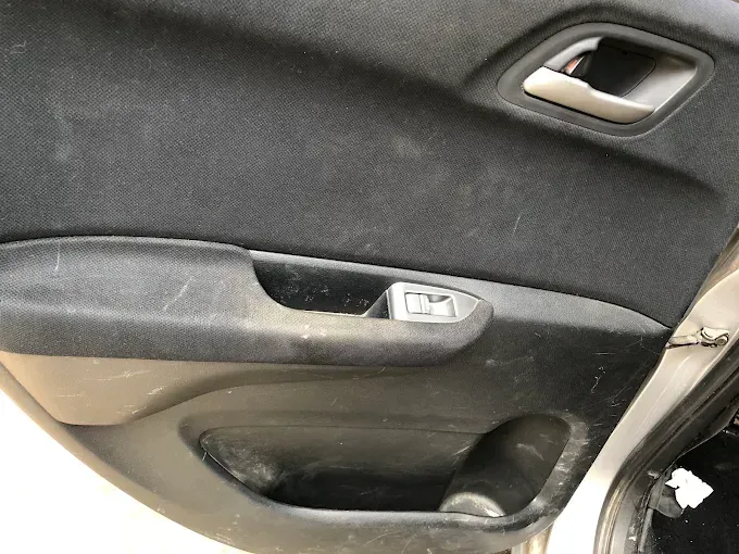 Primer plano del panel interior de la puerta de un coche negro con manija plateada y bolsillo de almacenamiento