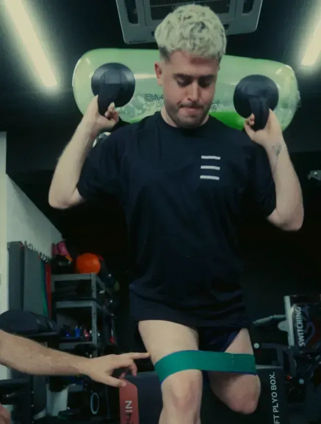 Un hombre con una camisa negra está haciendo ejercicios con una banda de resistencia.