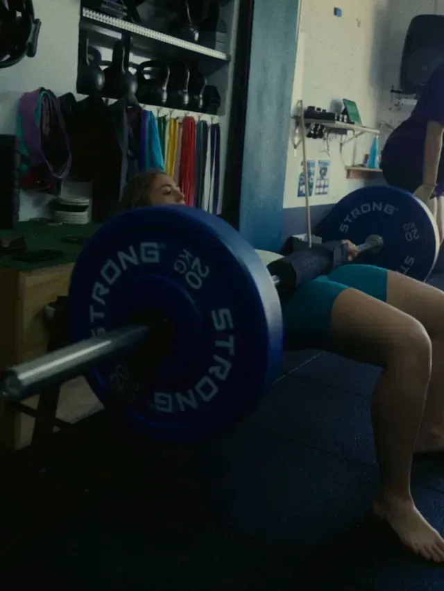 Una mujer está en cuclillas con una barra que dice 