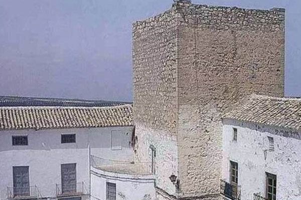 Una torre de castillo está rodeada por una hilera de edificios blancos.
