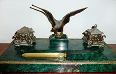 Una estatua de un águila está sentada encima de un tintero de mármol.