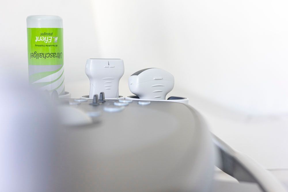 Nahaufnahme eines medizinischen Geräts mit zwei Applikatoren und einer Gelflasche vor weißem Hintergrund.