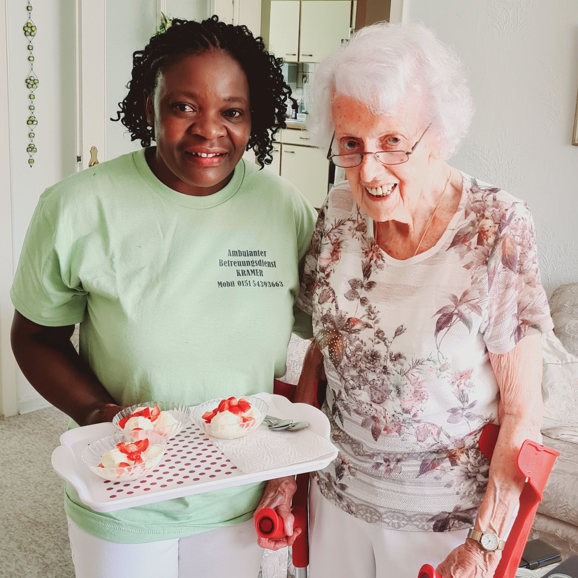 Eine Frau in einem grünen Hemd steht neben einer älteren Frau mit Krücken