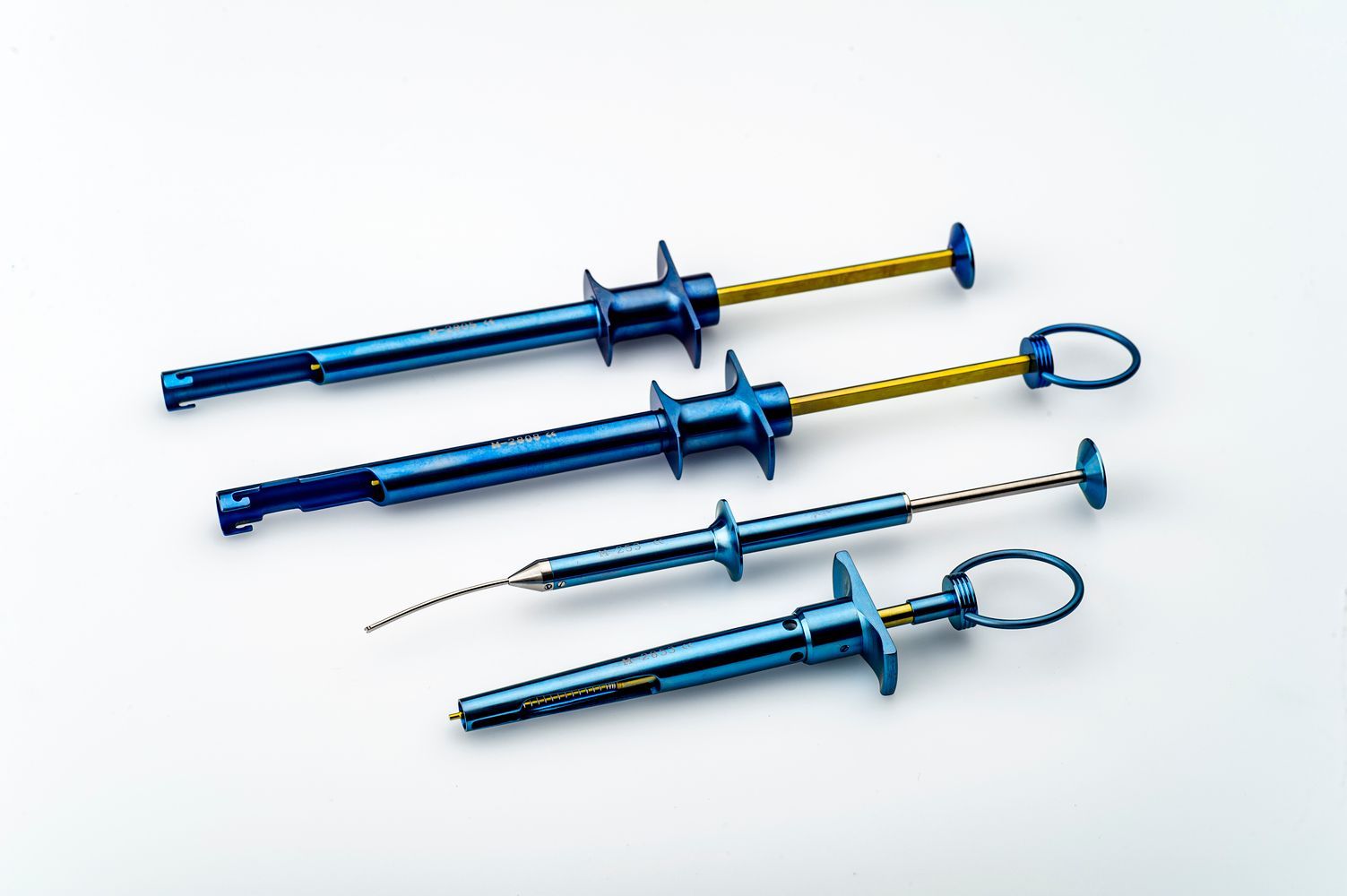Tres jeringas azules con mangos amarillos sobre una superficie blanca