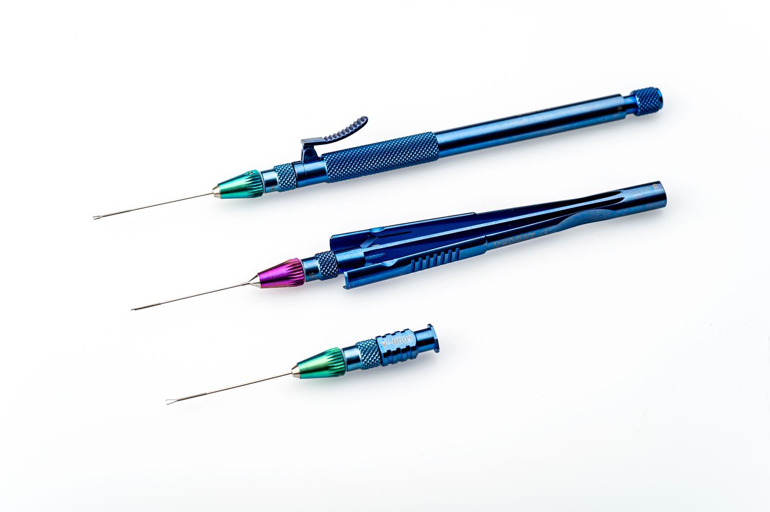 Tres bolígrafos azules con puntas de colores están sobre una superficie blanca.