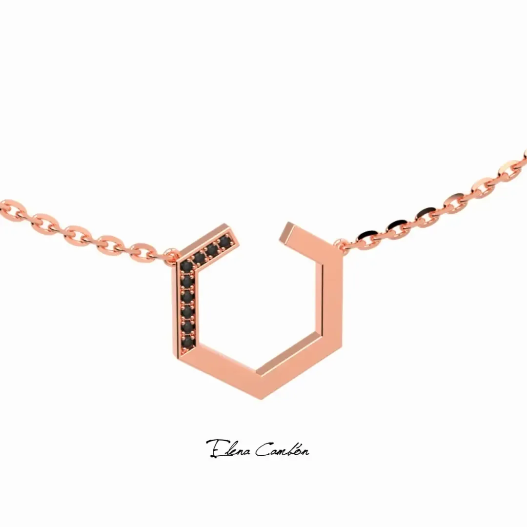 Collar geométrico de oro rosa con piedras negras sobre fondo blanco.