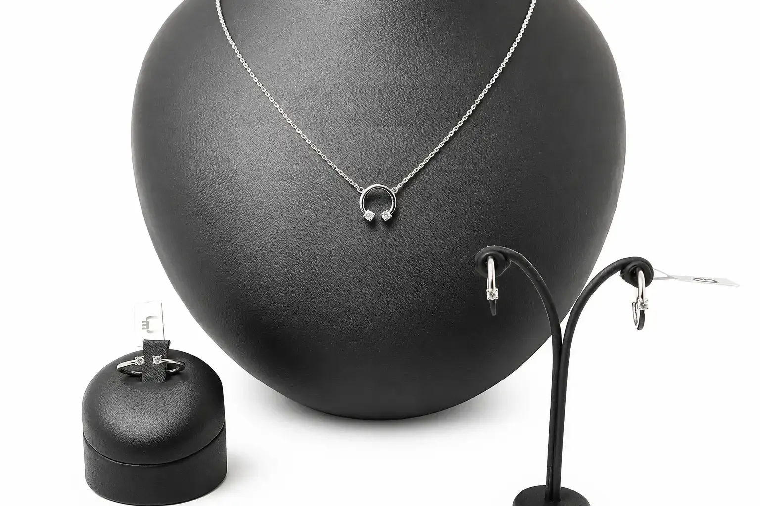 Exhibidor de collar negro con pendientes a juego sobre soporte de busto y soportes para joyas.