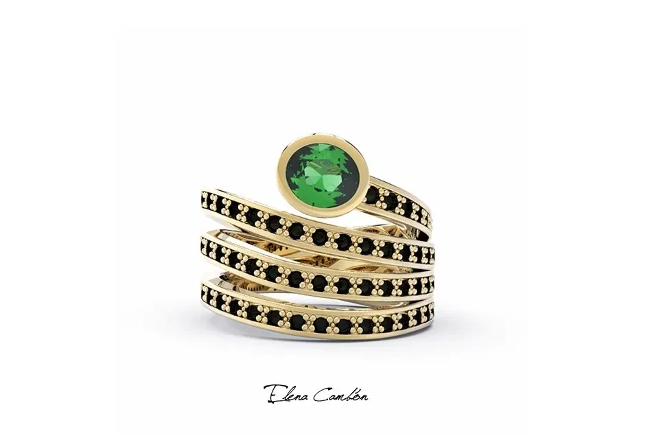 Anillo de oro con bandas apiladas de piedras negras y una gema redonda verde en el centro.