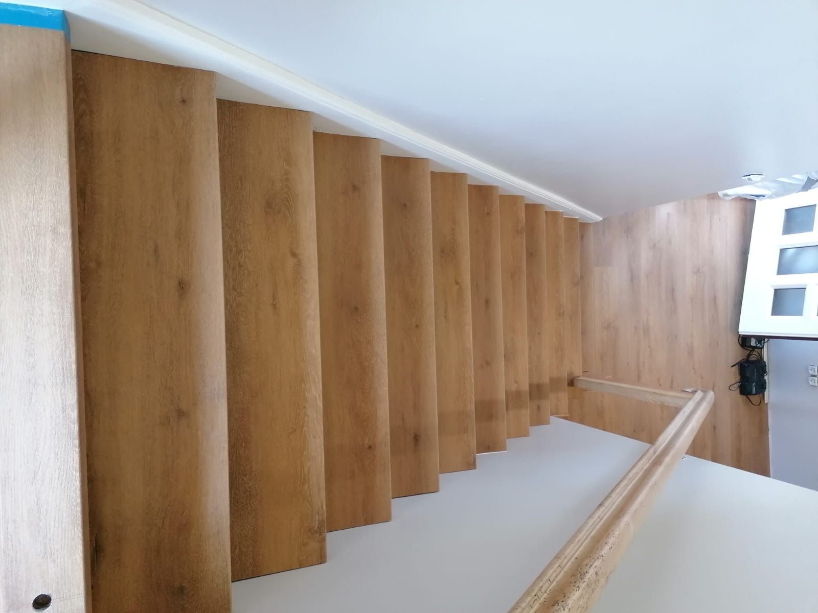 Nach oben führende Holztreppe, helle Holztöne, weiße Wände und Zierleisten.