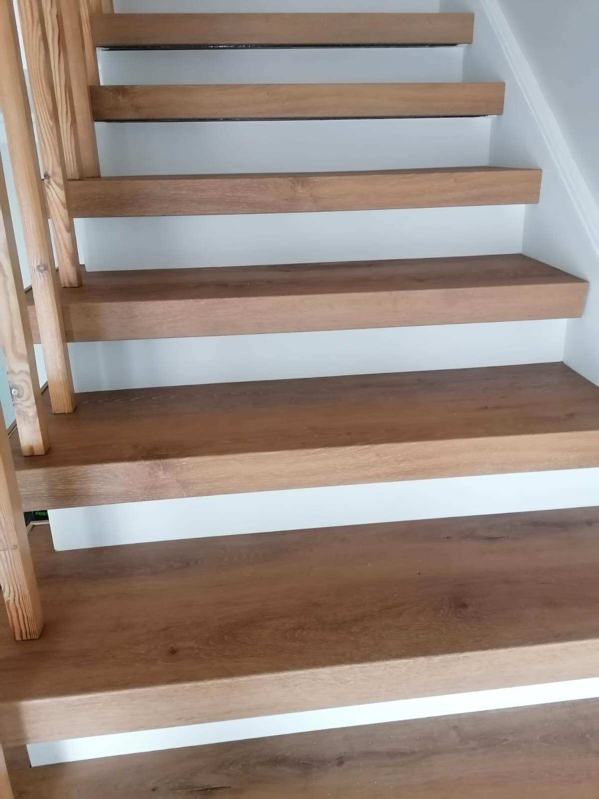 Holztreppe mit weißen Setzstufen und Holzgeländer.