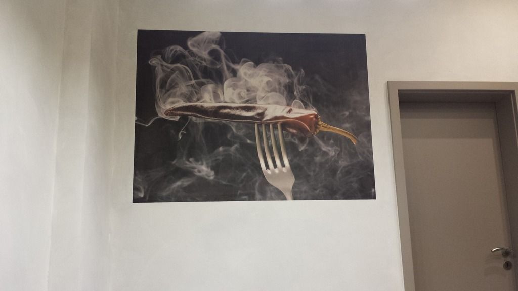 Ein Lebensmittelfoto einer Wurst auf einer Gabel mit Rauch an einer Wand.