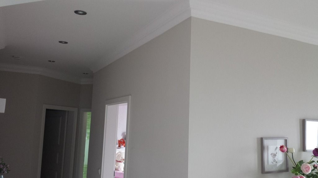 Innenecke mit weißer Kronenleiste, grauen Wänden, Einbauleuchten.