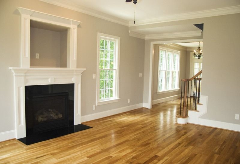 Wohnzimmer mit Kamin, Fenstern, Hartholzböden und grauen Wänden.