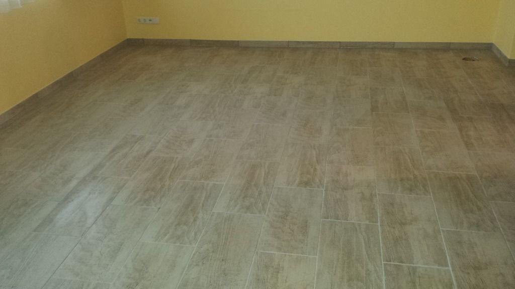 Leerer Raum mit hellbraunem Fliesenboden und gelben Wänden.