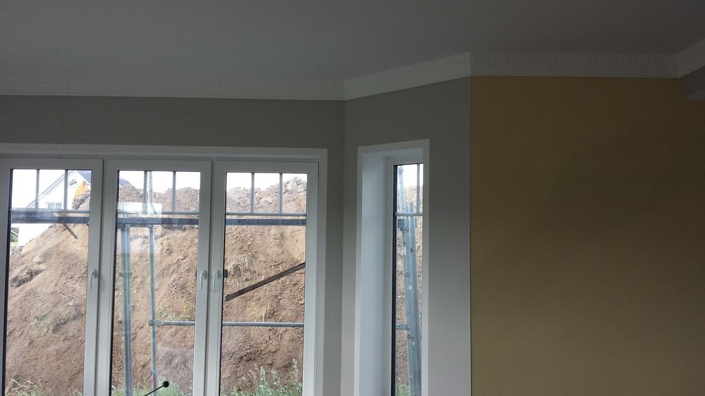 Zimmerecke mit Fenstern, in Weiß, Grau und Gelb gestrichene Wände; weiße Zierleiste.