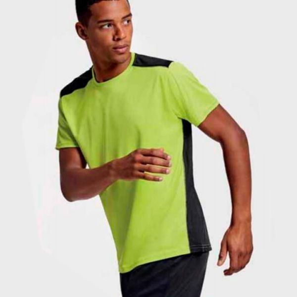 Un hombre que lleva una camiseta verde neón y pantalones cortos negros está corriendo
