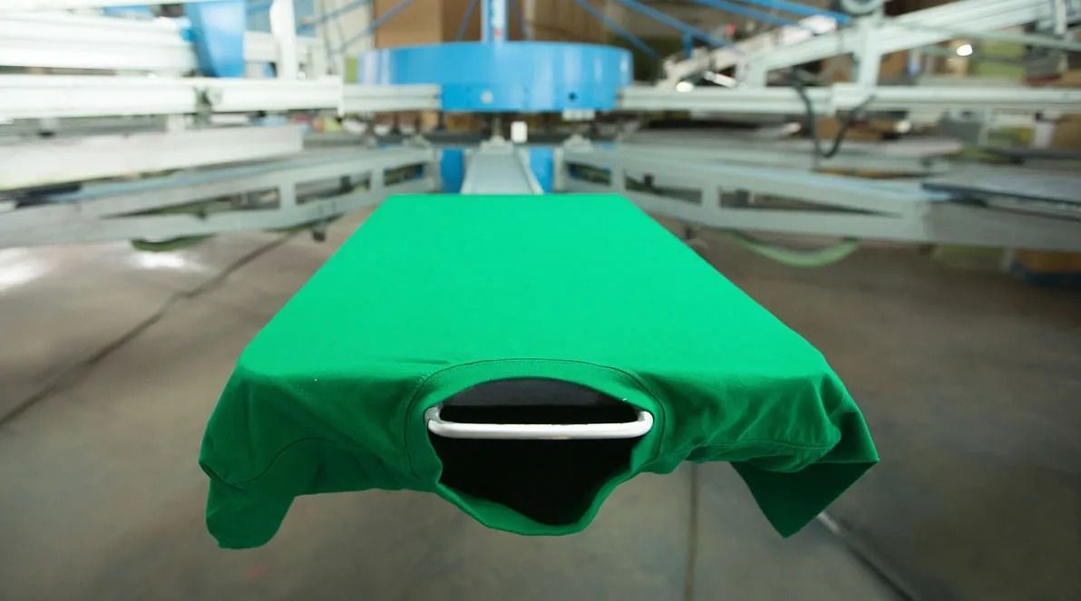 Se está imprimiendo una camiseta verde en una máquina en una fábrica.