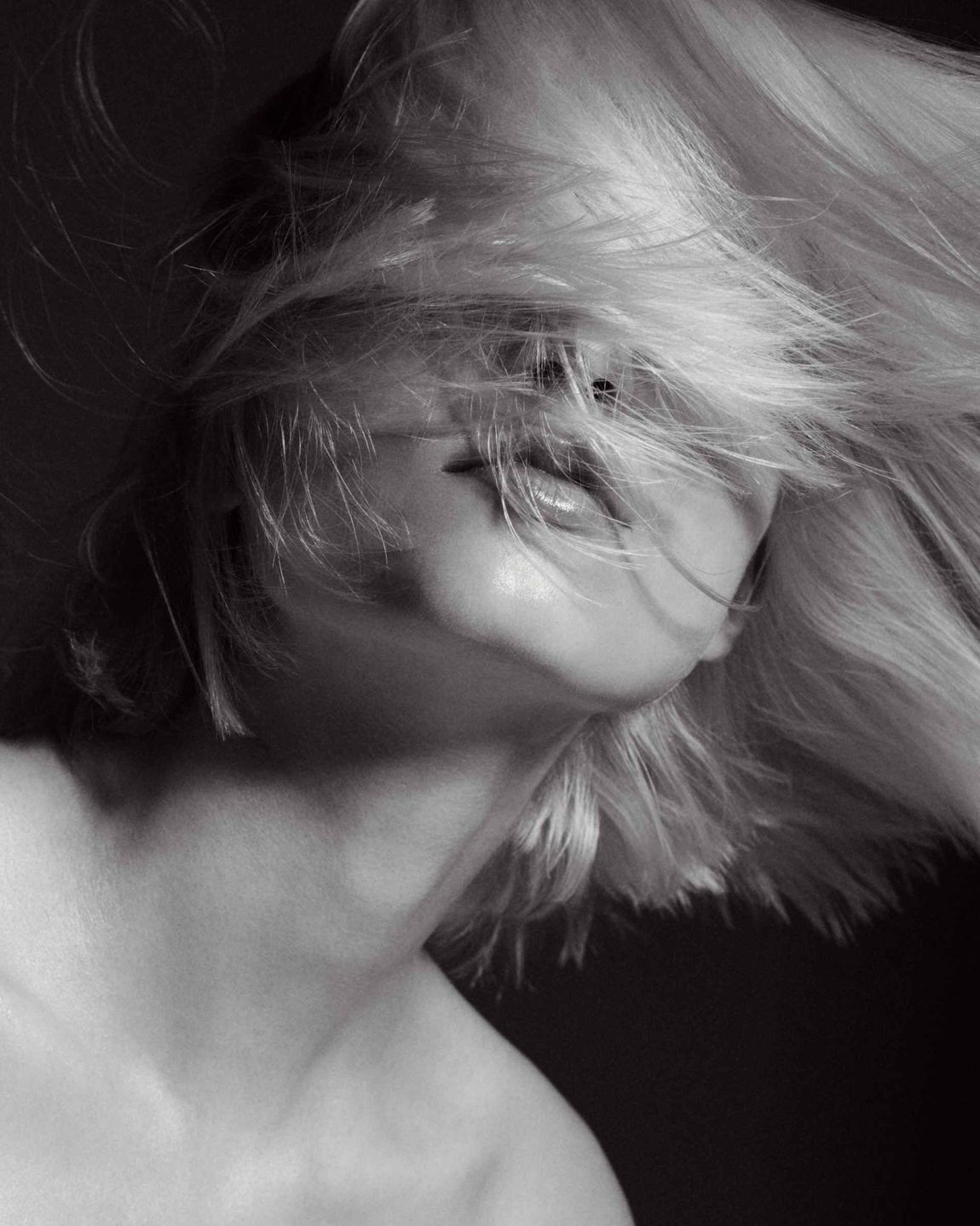 Frau mit blonden Haaren, die das Gesicht verdecken, Kopf nach oben geneigt, in Schwarzweiss.