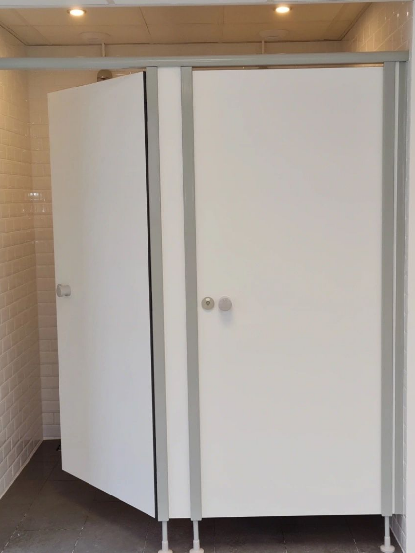 Portes de cabine de salle de bains blanches, cadre et quincaillerie gris, pieds gris, aménagement intérieur.