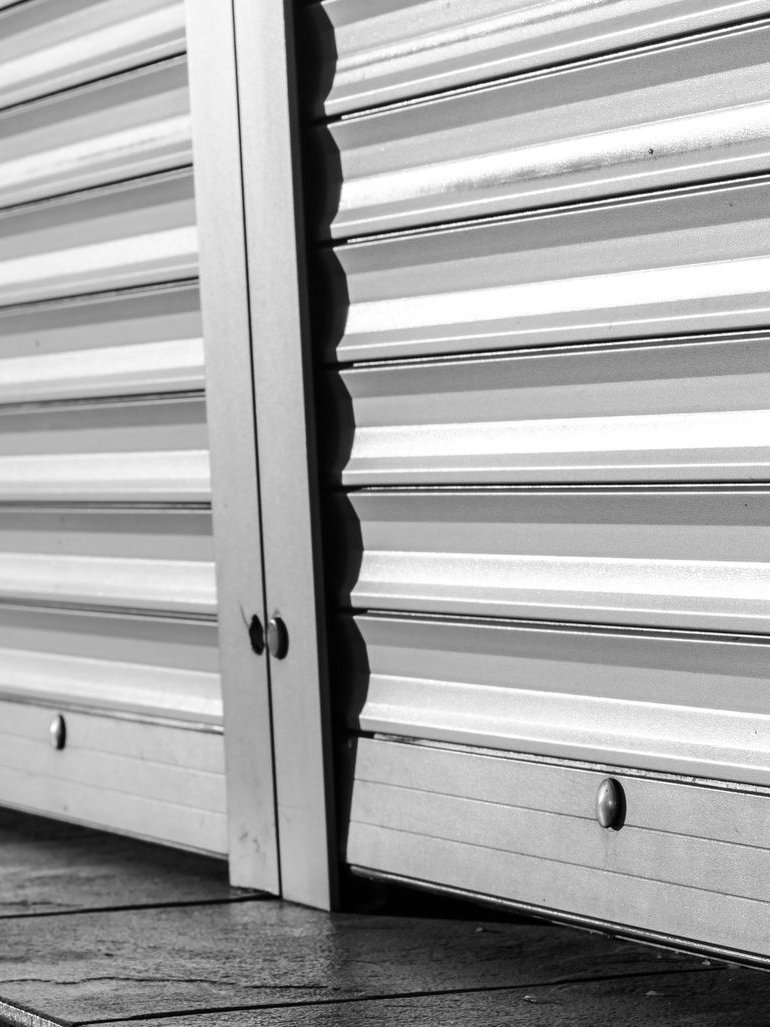 Portail à enroulement partiellement ouvert ; gros plan montrant les lattes métalliques, les détails des bords et le sol.