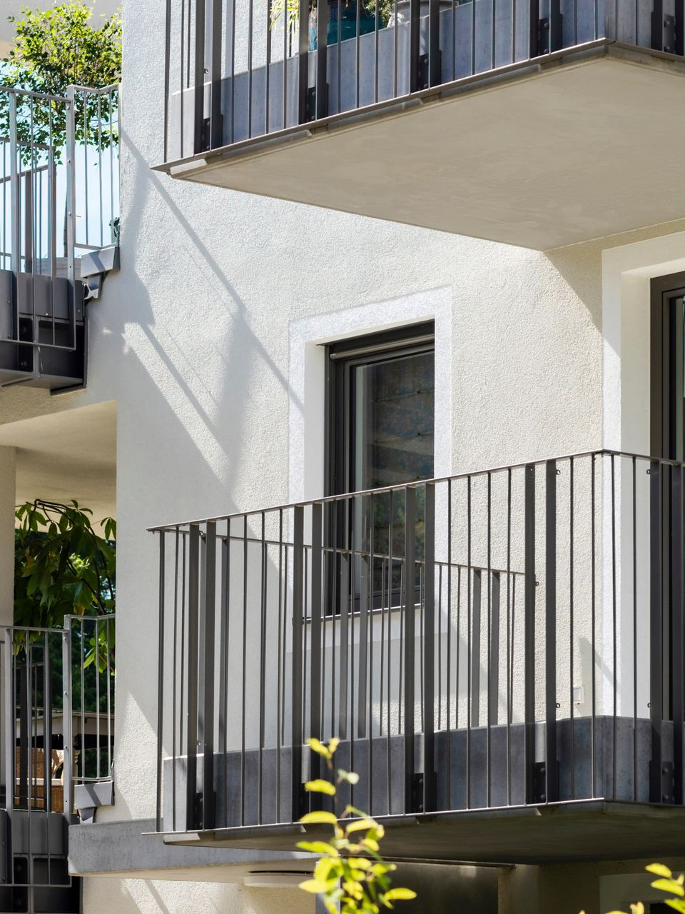 Vue extérieure d'un bâtiment blanc avec des balustrades et des balcons sombres.