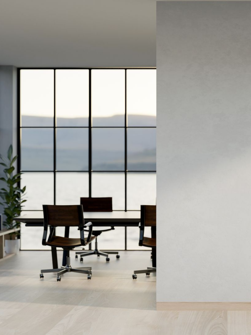 Bureau avec une longue table, des chaises et de grandes fenêtres donnant sur un lac. Lumière douce et couleurs neutres.