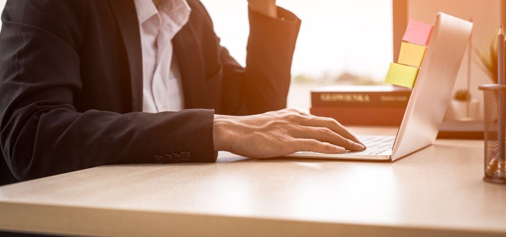 Un hombre con traje está sentado en un escritorio utilizando una computadora portátil.
