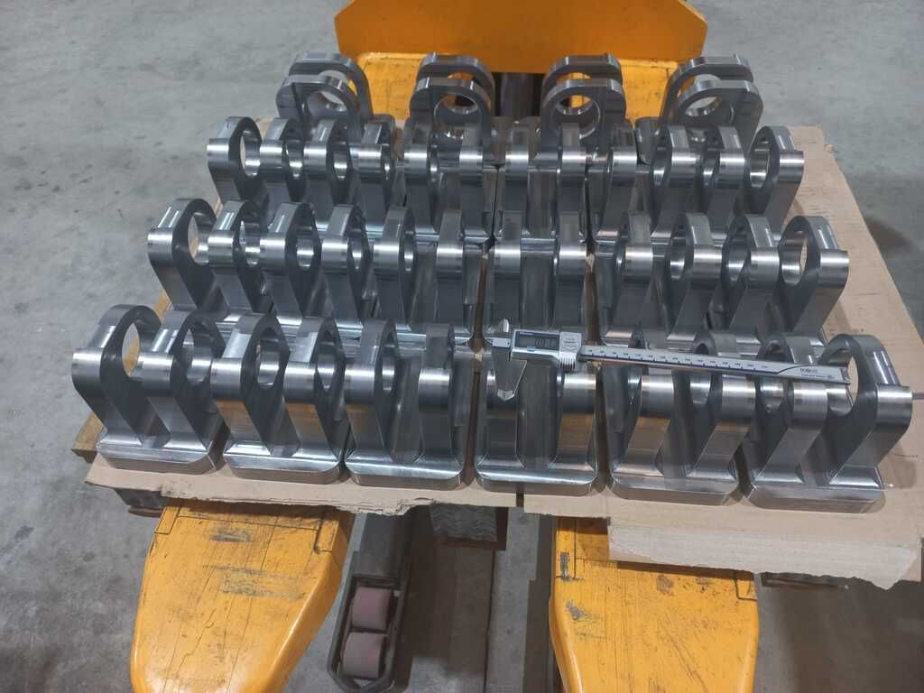 Un montón de piezas de metal están apiladas una encima de otra en un palé amarillo.