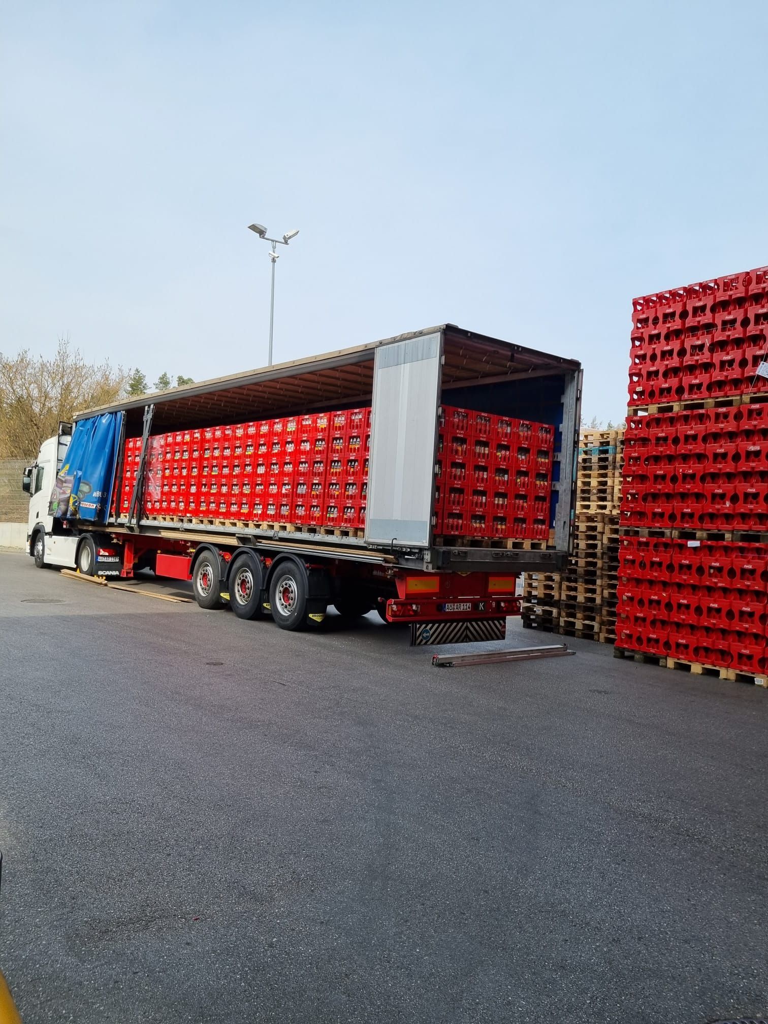 Ein mit Kisten beladener Lastwagen steht neben einem Stapel Kisten.
