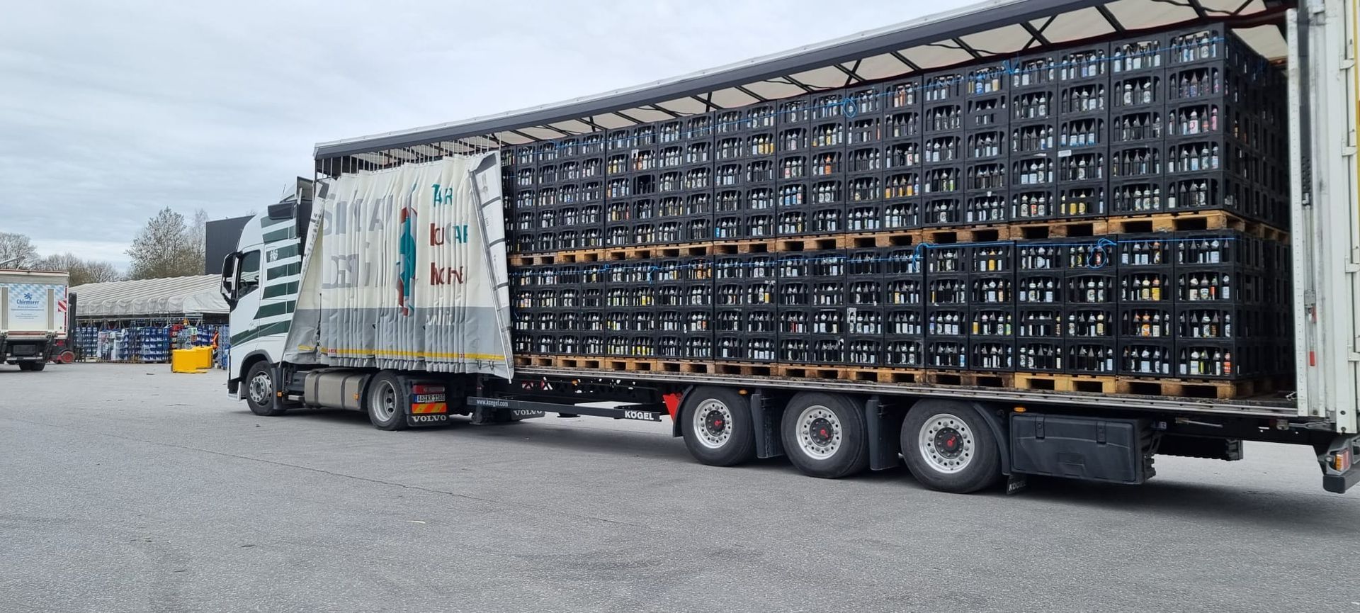 Auf einem Parkplatz steht ein mit Kisten beladener Sattelschlepper.