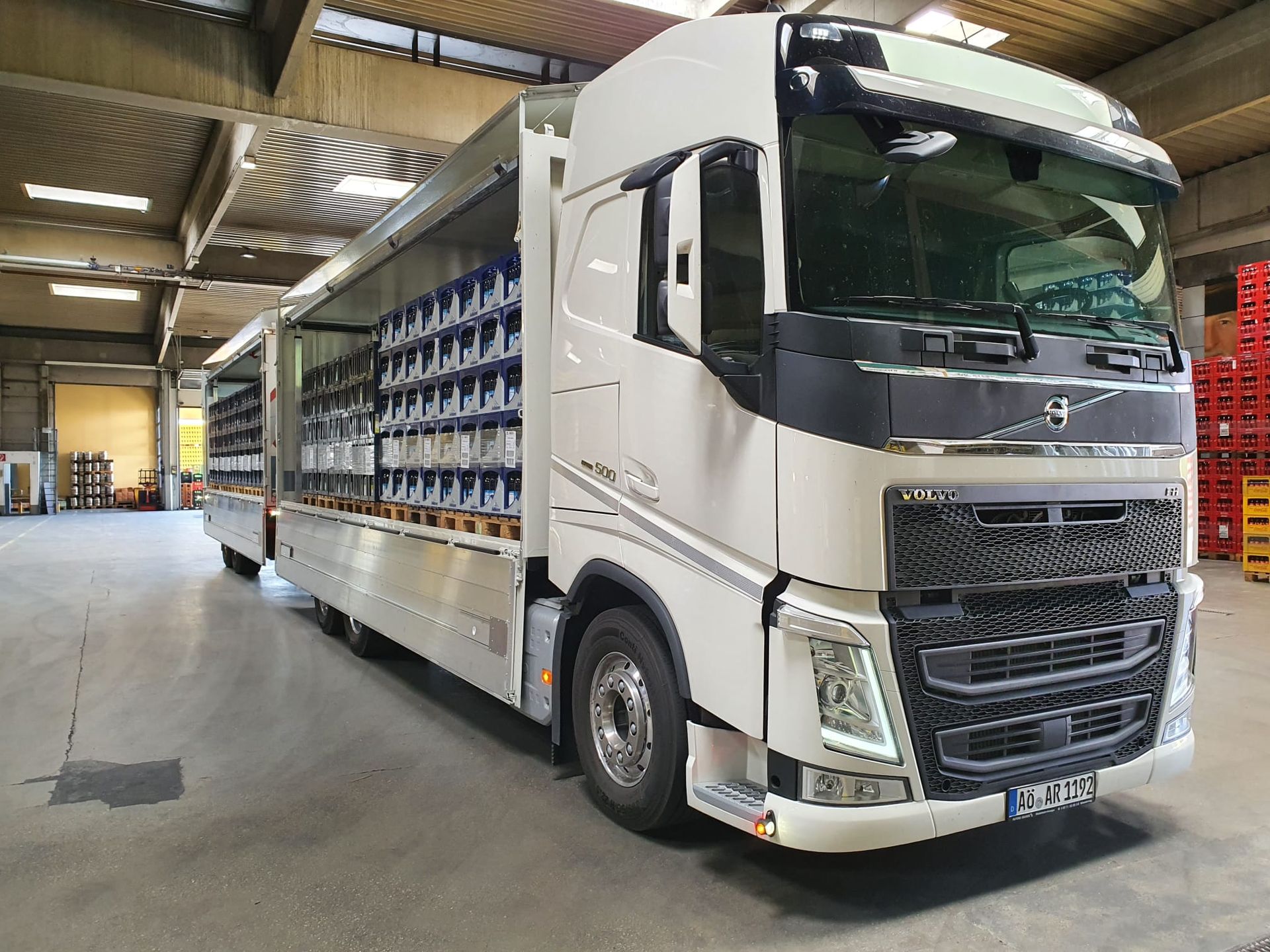 Ein weißer Sattelschlepper steht mit offenen Türen in einem Lagerhaus.