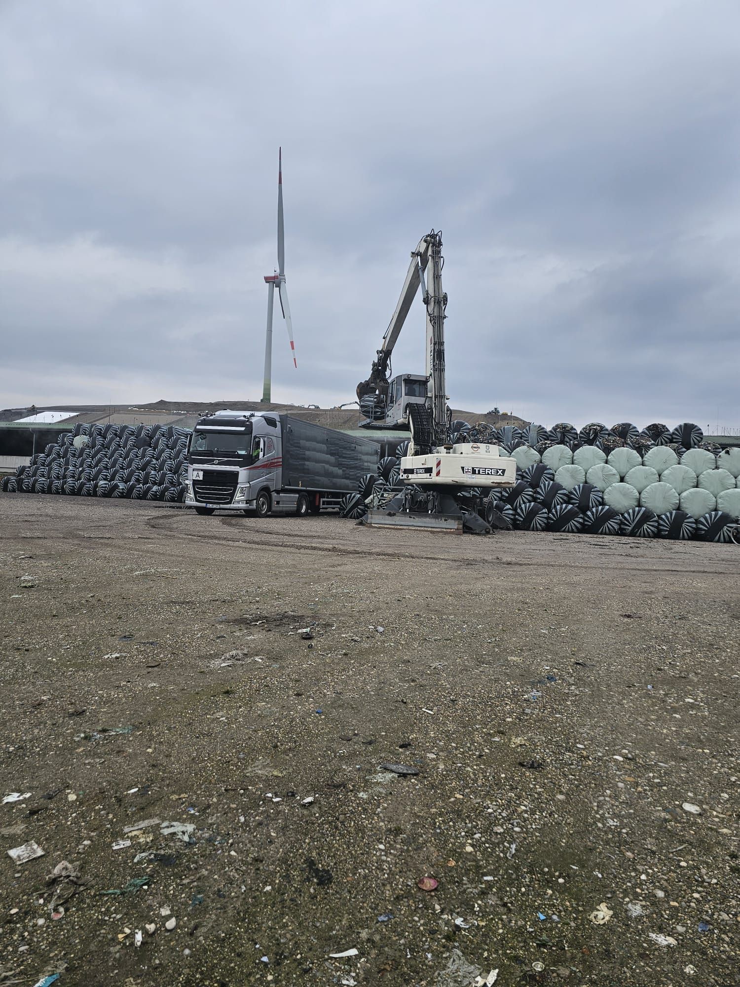 Auf einem Feld wird ein Lastwagen mit Heuballen beladen.