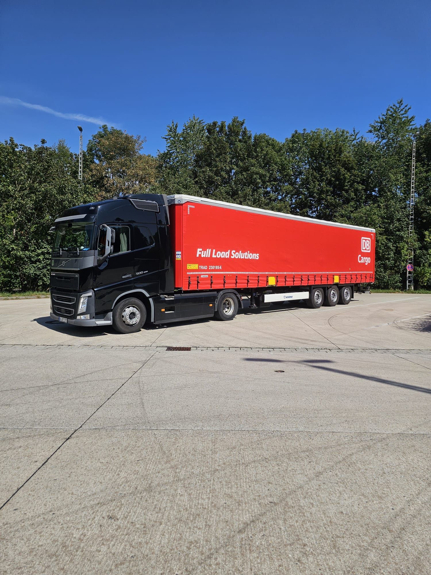 Ein rot-schwarzer Sattelschlepper steht auf einem Parkplatz.