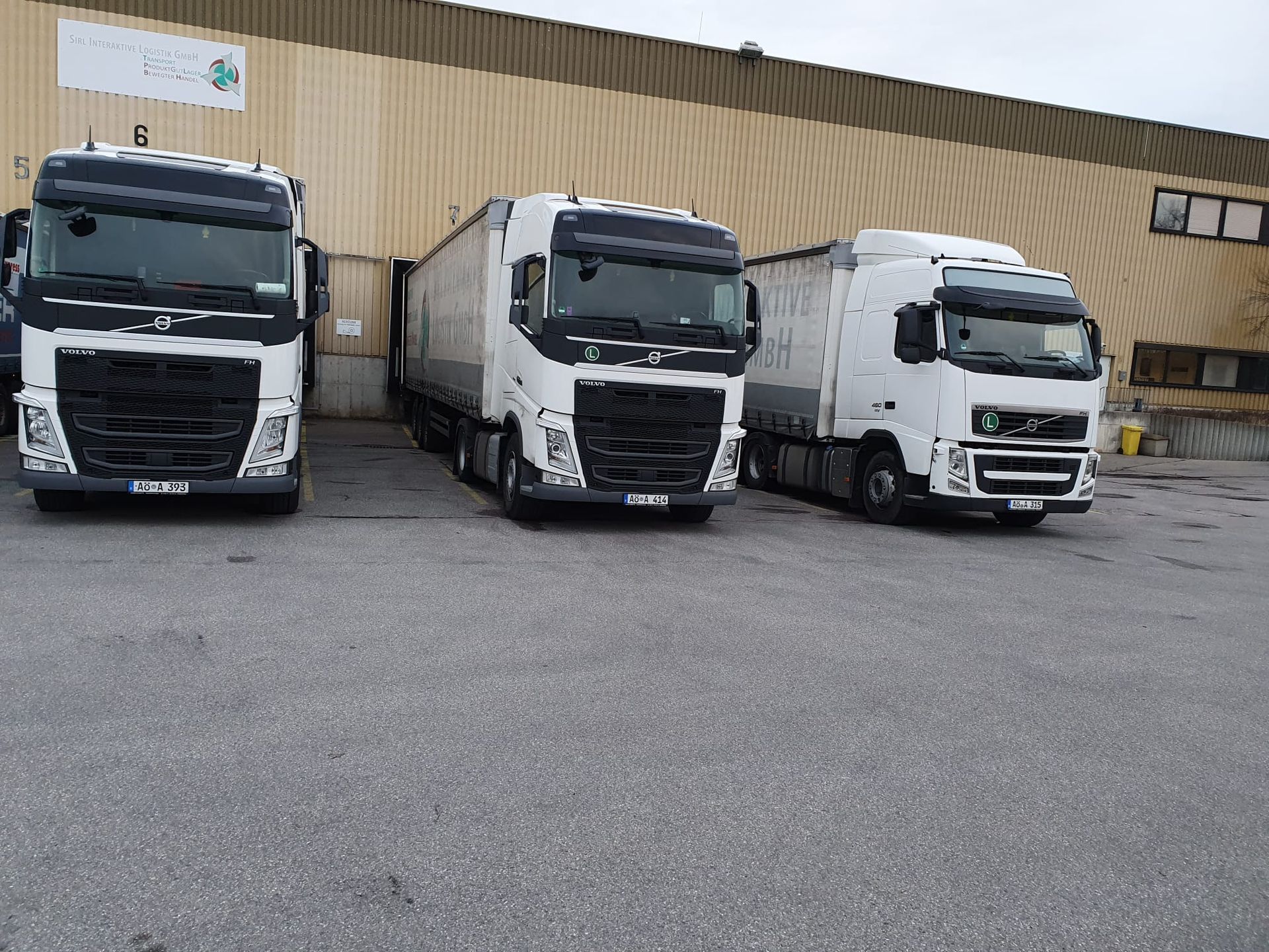Drei weiße Lastwagen parken vor einem Gebäude.