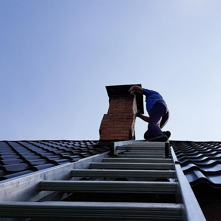 Professionnel montant à l'échelle pour ramoner la cheminée