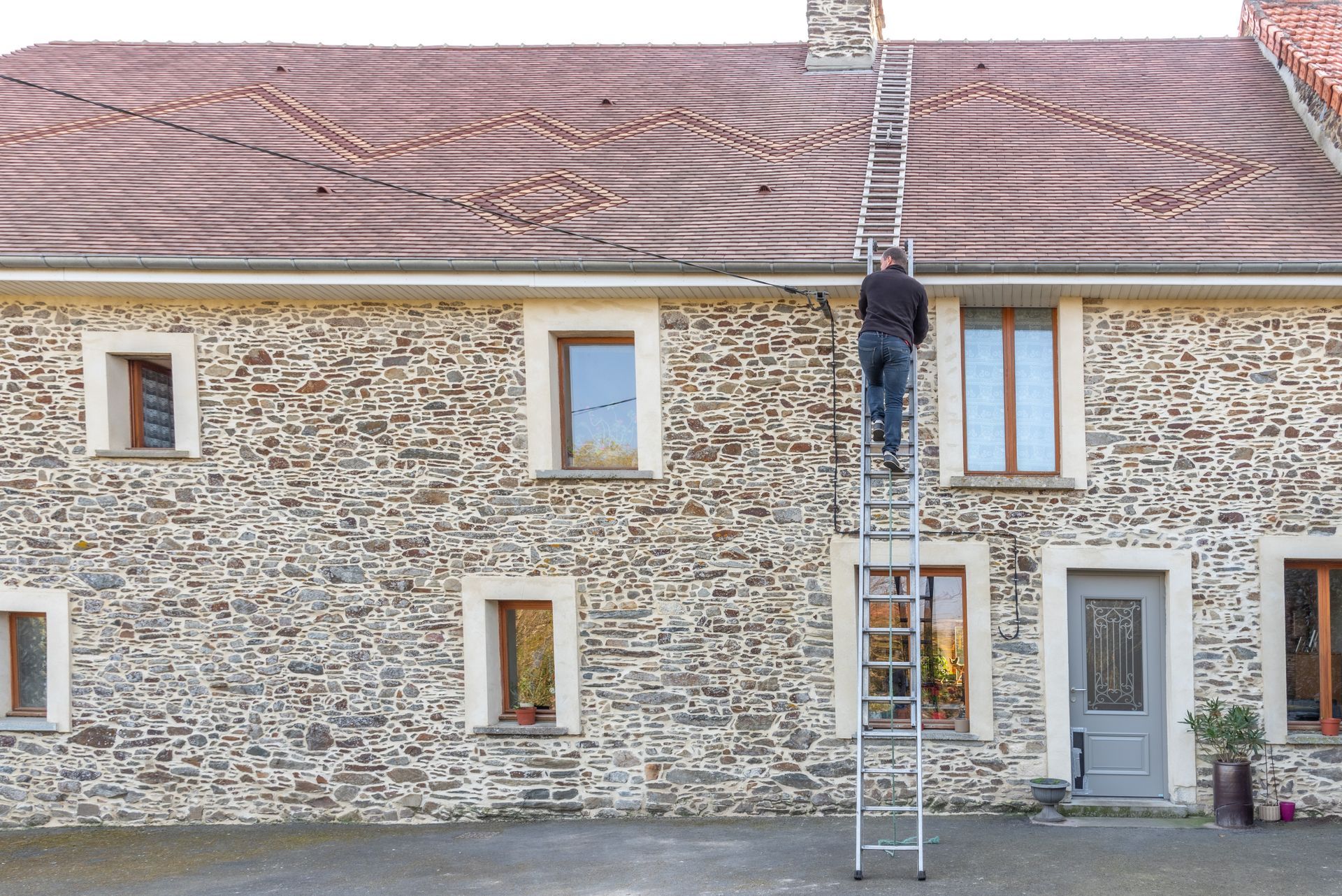 Membre de l'entreprise Lyaouanc Père et Fils montant sur la toiture avec une échelle