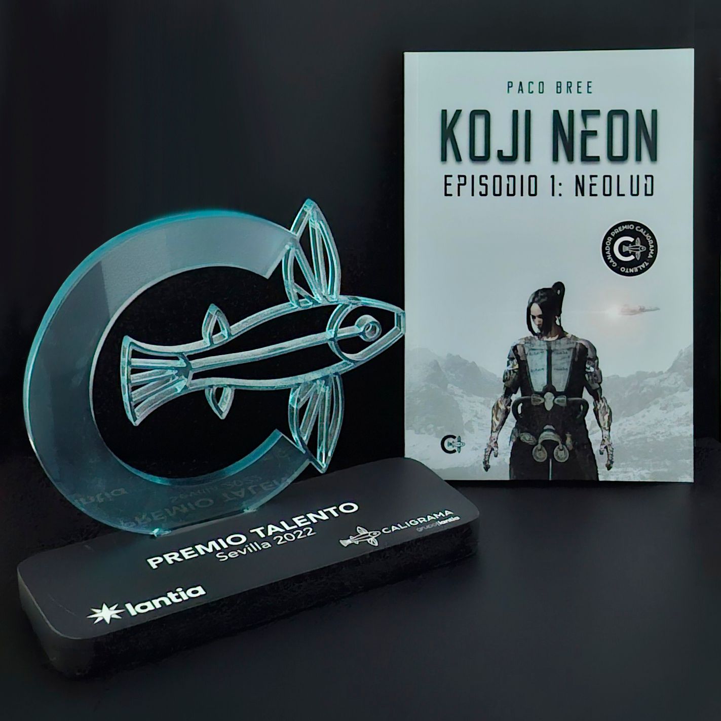 Un libro llamado Koji Neon está al lado de un trofeo.