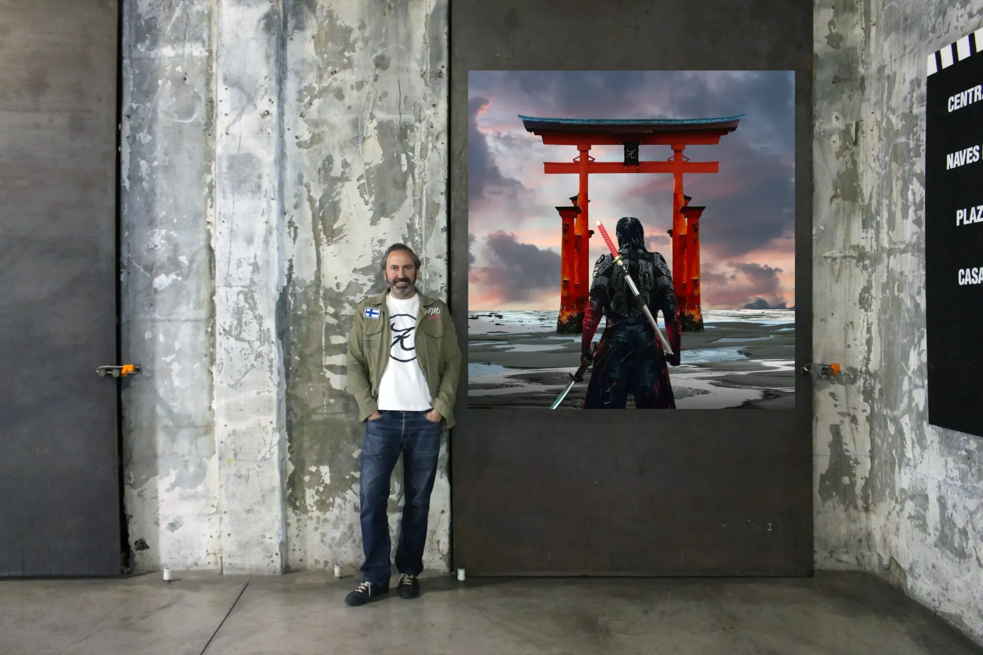 Un hombre está sentado en un sofá rojo al lado de una mesa con libros encima.