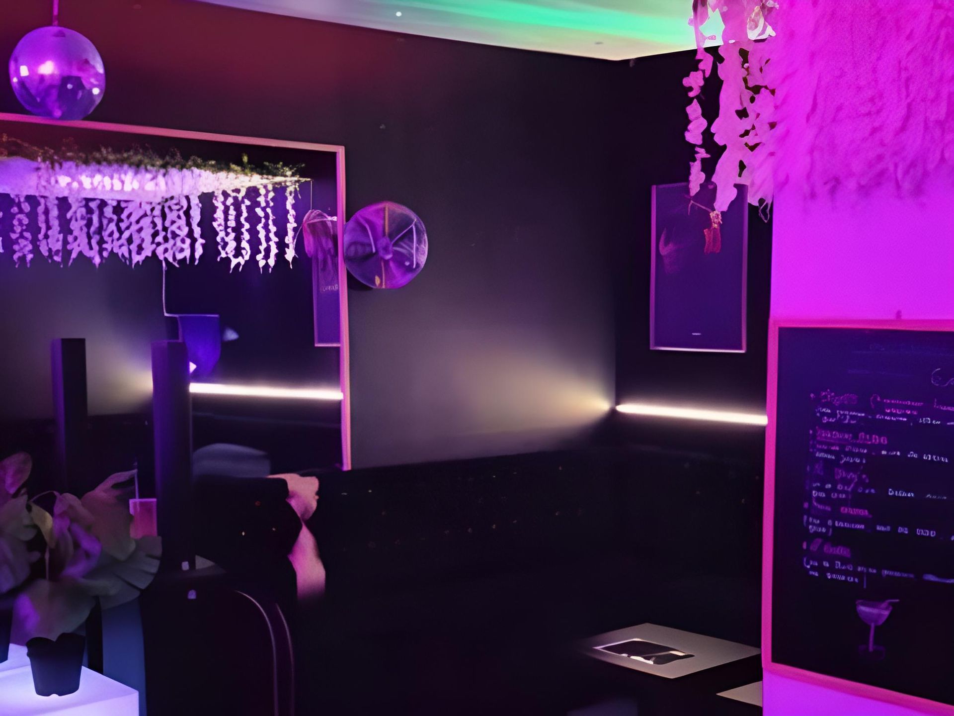 Intérieur de bar sombre, boules disco, éclairage néon, tableau des menus, plantes et œuvres d'art.