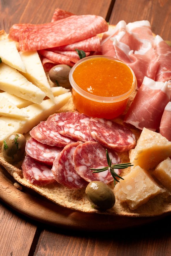 Planche de charcuterie avec salami, prosciutto, fromage, olives et marmelade d'orange.