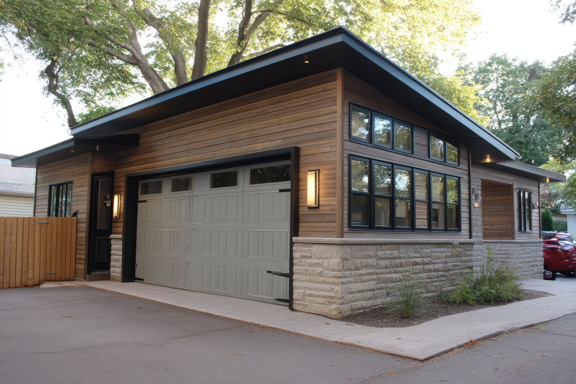Garage moderne avec revêtement en pierre et en bois, grandes fenêtres et porte de garage beige.