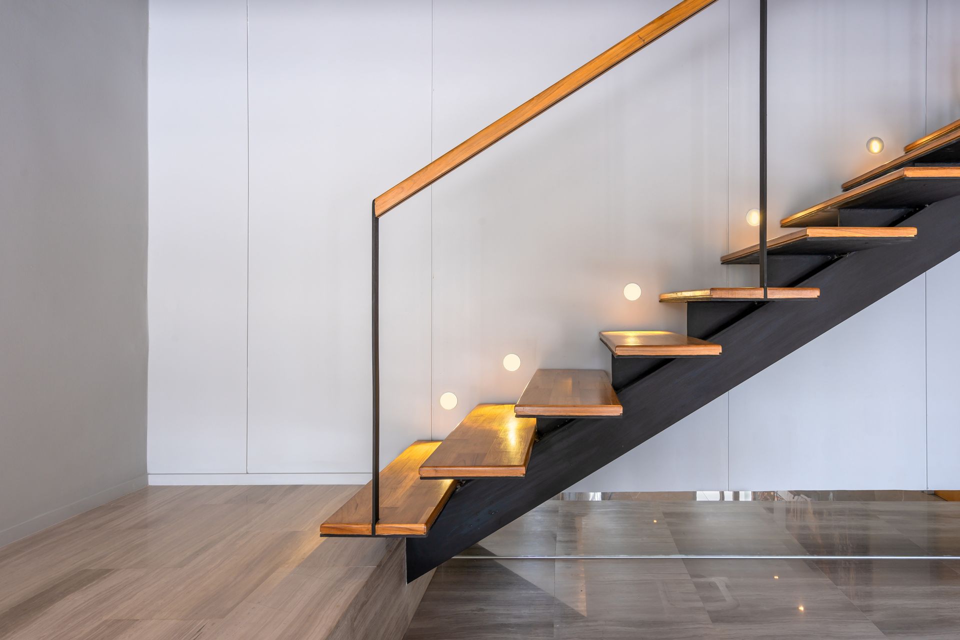 Escalier en bois avec support noir et lumières intégrées ; rampe en bois, intérieur moderne.