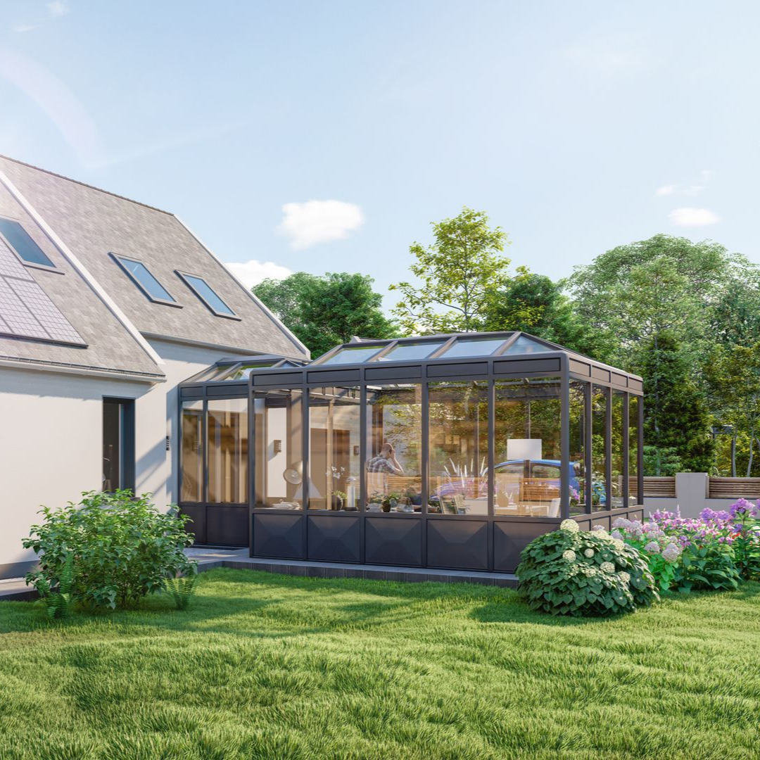 Une véranda moderne en verre attachée à une maison dans une cour arrière ensoleillée, entourée d'herbe verte et d'un jardin.