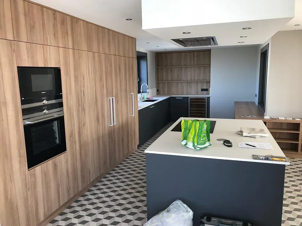 Cuisine moderne avec armoires en bois, îlot et électroménagers.