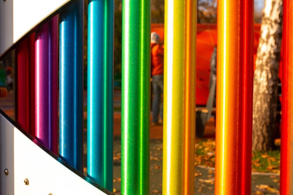 Un primer plano de una valla de color arcoíris con una persona en el fondo.